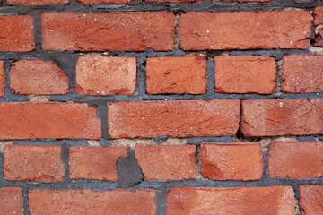 Obraz premium Old red brick wall. Bricks with individual texture with concrete layering .
