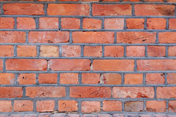 Old red brick wall. Bricks with individual texture with concrete layering .