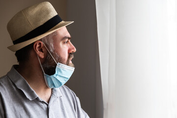 Un hombre lleva mascara para potegerse del covid19 coronavirus para no contagiarse.  mira a traves...