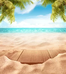 Deurstickers Tropical fine sandy beach with blured sea sun sky clouds background with wooden table top and empty space for product advertisement Montage of summer relaxation background © OHishi_Foto