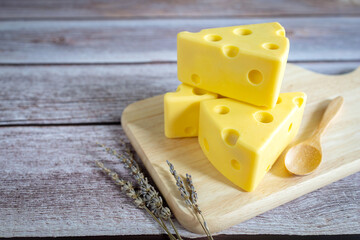 Three cheese on wooden tray on rustic wooden table.