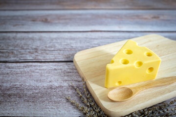 piece of cheese on wooden tray on rustic wooden table.