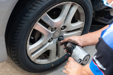 Unidentifield automobile engineer use wind block and hand change new car tire instead the bald tyre.