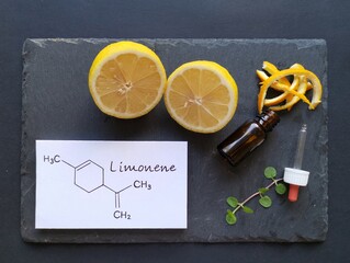 Structural chemical formula of limonene with fresh citrus fruit and a glass bottle of essential...