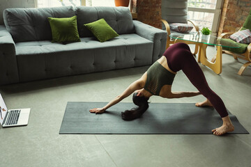 Asana. Sporty beautiful young woman taking professional yoga lessons online and practice at home....