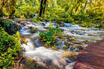 Wonderful summer view of Skradinski Buk waterfall with wooden bridge. Bright morning scene of Krka National Park, Lozovac village location, Croatia, Europe. Beautiful world of Mediterranean countries.