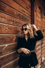 Photo session of a stylish girl outdoors. Young model on a background of a wooden barn.
