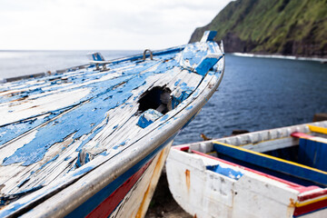 Old colourful wooden boats with peeling paint. Azorean island old harbour.