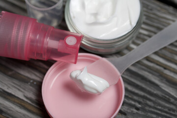 Plastic bottle with cream. The cover is removed and lies nearby. Near the shoulder blade, on it a cream. Against the background of pine boards.