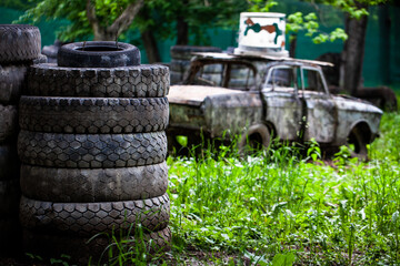 Paintball shooting range. Paintball territory in the forest. Iron barrels in the foreground with multi-colored blots and smudges from shots from the paintball weapon. Old tires from a car and trees. 
