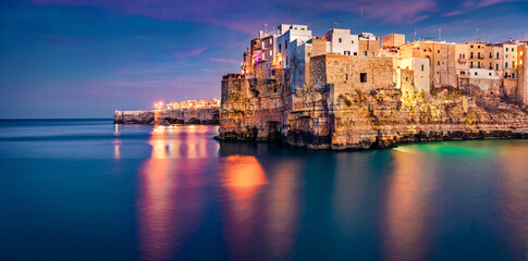 Fototapeta premium Calm evening cityscape of Polignano a Mare town, Puglia region, Italy, Europe. Illuminated old houses on the chore of Adriatic sea. Traveling concept background.