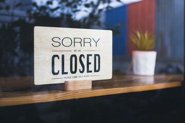 Sorry we're closed wooden sign. on a dirty glass windows.