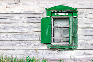 Part of the wall and green shutters in an abandoned rural wooden house.