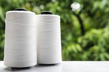 Raw White Polyester FDY Yarn spool with green blurred background