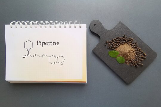 Structural chemical formula of piperine molecule with ground black pepper powder and black pepper grains. Piperine is an amide alkaloid, isolated from Indian medicinal plant Piper nigrum.