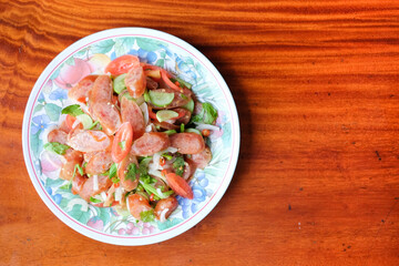 Chinese sausage spicy salad serve on white dish set on brown table - homemade food concept.