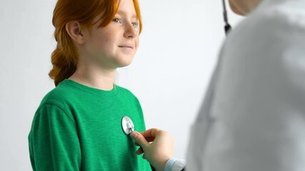 Female doctor listening to lungs and heartbeat of young girl with stethoscope