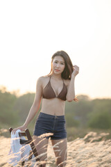 Beautiful blonde women in a brown bikini on a brown meadow with white flowers in the summer evenings.