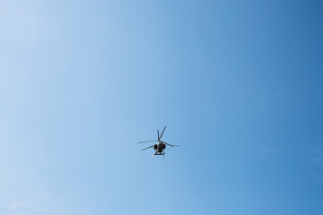 Small civil helicopter flies against a blue sky background