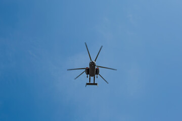 Fototapeta na wymiar Small civil helicopter flies against a blue sky with clouds background