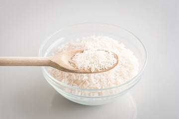 Long Grain Dry Raw White Rice on a transparent bowl and a wooden spoon