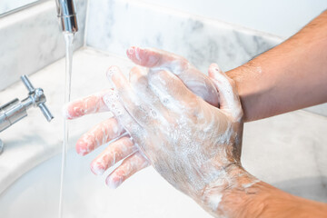 Fototapeta premium White Male Hands Being Cleansed With Soap and Water On a Bathroom Sink