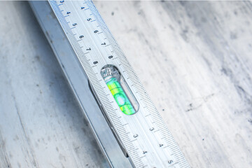 Aluminum spirit level lies on a smooth metal surface. Close-up. Top view.