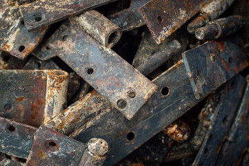 Background from heaps of old rusty metal door hinges. Selective focus. Raw materials for metal recycling