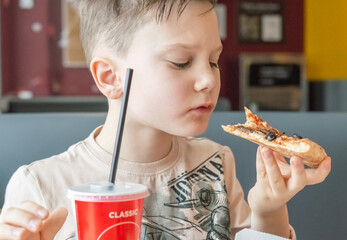 Child, boy eating pizza in a pizzeria
