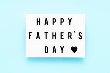HAPPY FATHER'S DAY written in light box on blue background, greeting card. Fathers Day celebration concept