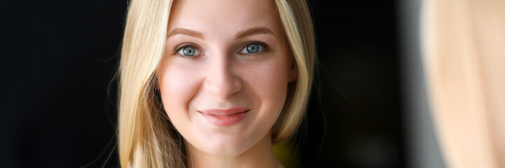 Obraz premium Smiling beautiful blonde woman looking in mirror