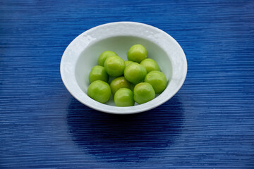 Fresh green plums harvested from tree in white bowl