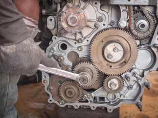 The mechanic is fixing the engine of the pick-up truck. By tightening the screw.