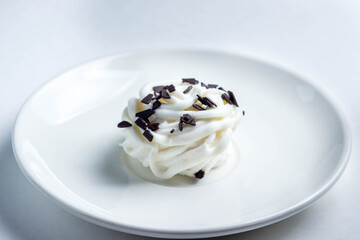 One white marshmallow sprinkled with dark chocolate. Marshmallows on a white plate. Dessert.