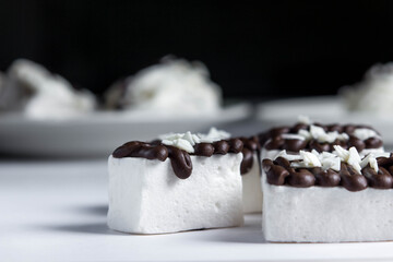 White marshmallow poured by dark chocolate. Marshmallows on a black background. Sweet cuisine