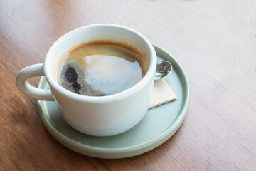 Cup of black coffee on wooden table.