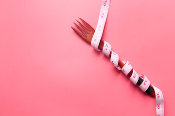 fork with measurement tape on pink background 