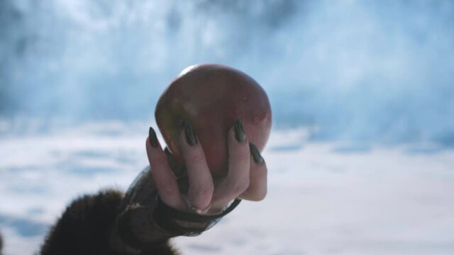 Close-up of a witch holding a red Apple at the forbidden fruit.
