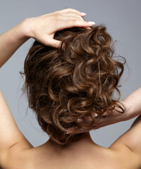 Naklejka premium Back view portrait of beautiful young dark brunette woman on gray background.