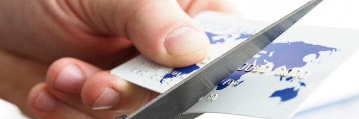 Male hand cutting banking card with scissors