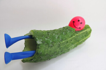funny cucumber figurine with blue legs and a pink head and smiling , white background