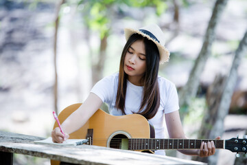 Portrait of beautiful girl playing the guitar with writing  at nature background