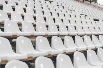 Stadiums amphitheater with many empty white plastic numbered seats for spectators in the stadium for football sport fans. Pattern of plain monochrome sport tribune.