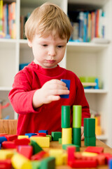 A young builder. kid building city from wooden blocks. Kids Play Room. Development and Construction Concept.