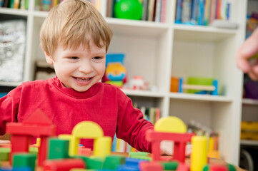 A young builder. kid building city from wooden blocks. Kids Play Room. Development and Construction Concept.