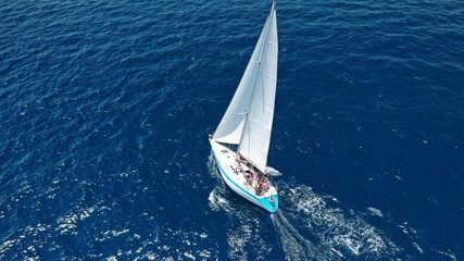 Aerial drone top down photo of beautiful sail boat cruising deep blue Aegean sea