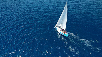 Aerial drone top down photo of beautiful sail boat cruising deep blue Aegean sea