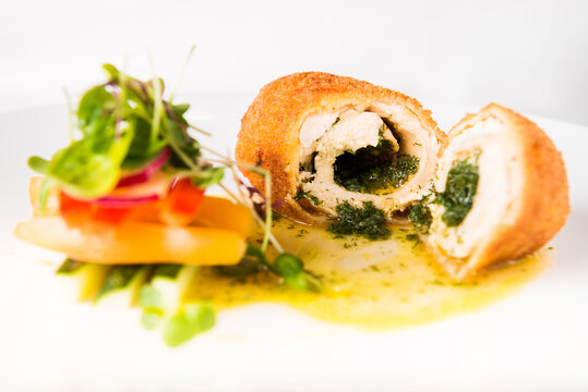 Fine Dining Russian Cuisine, Cut Chicken Kiev With Herbs And Mixed Salad, Close Up. Portion Of Chicken Kiev On The Plate.