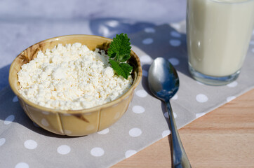 A plate of fresh homemade cottage cheese with mint leaves, a glass of milk and a spoon. Healthy eating concept. Breakfast.