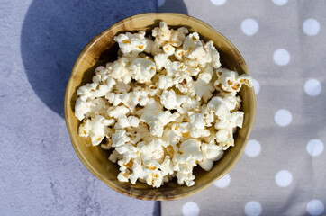 Popcorn in a brown bowl close-up top view.
